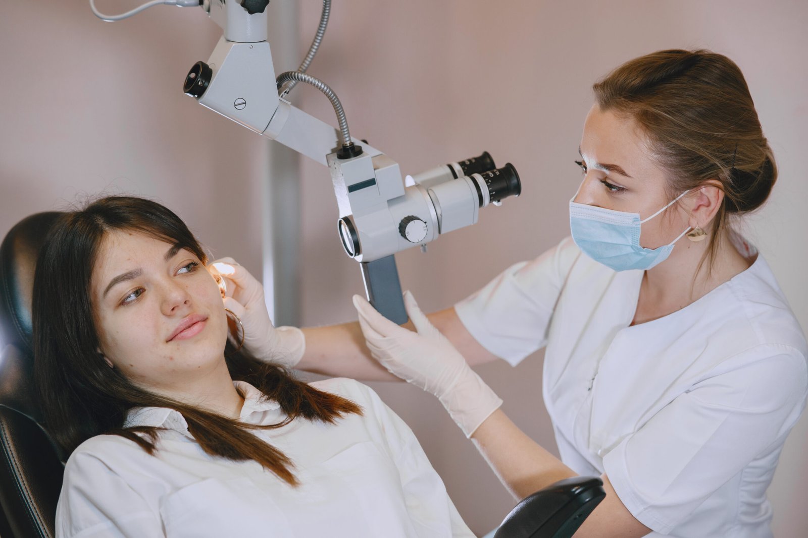 A woman sitting in a dental chair while a dentist examines her teeth during a routine check-up.