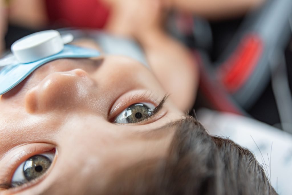 A child with a pacifier in his mouth, sitting in a medical setting at Retina Hospital in Indore for ROP screening.