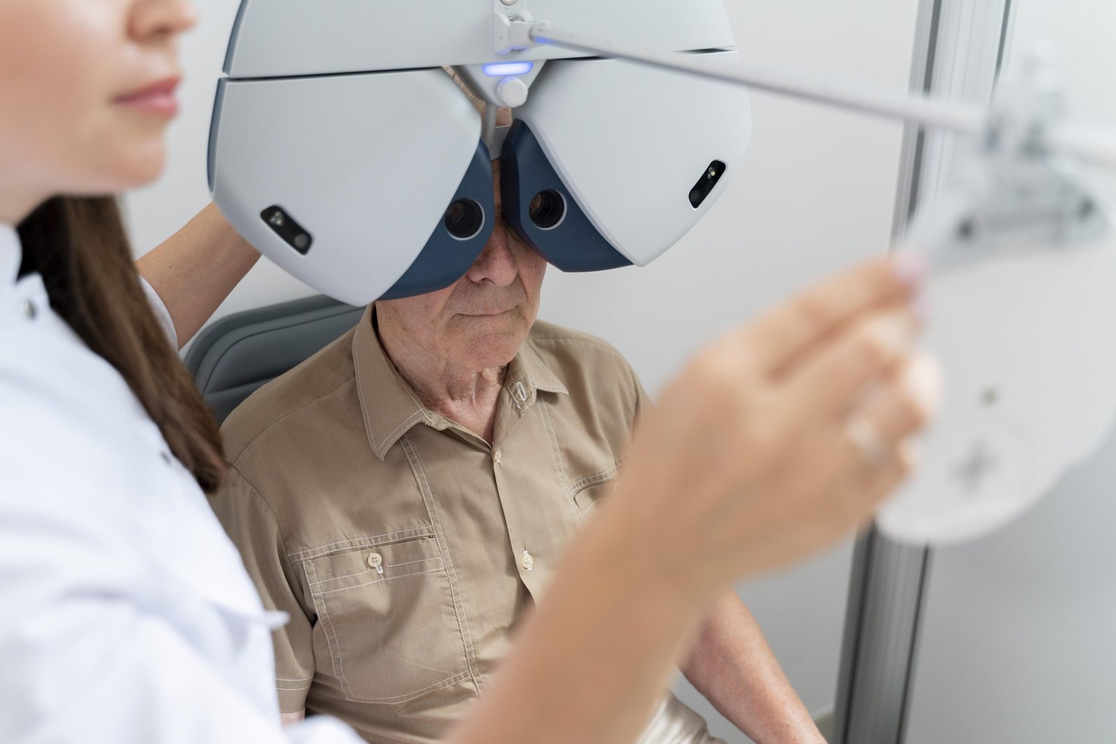 A retina specialist examines an elderly man using an eye exam machine in a clinical setting.